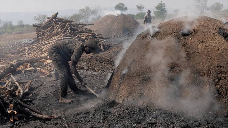 A worker tending traditional charcoal kilns